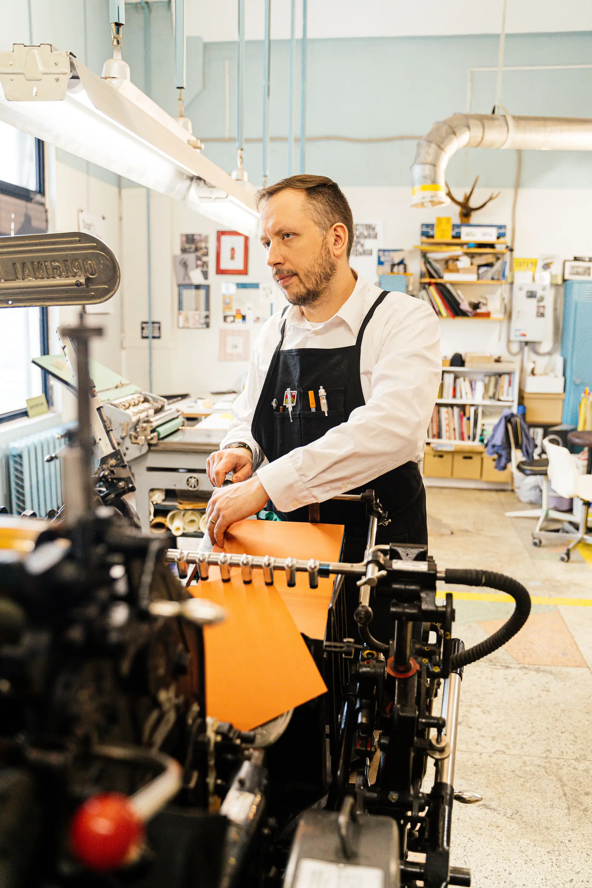 Artisan operating a vintage printing machine